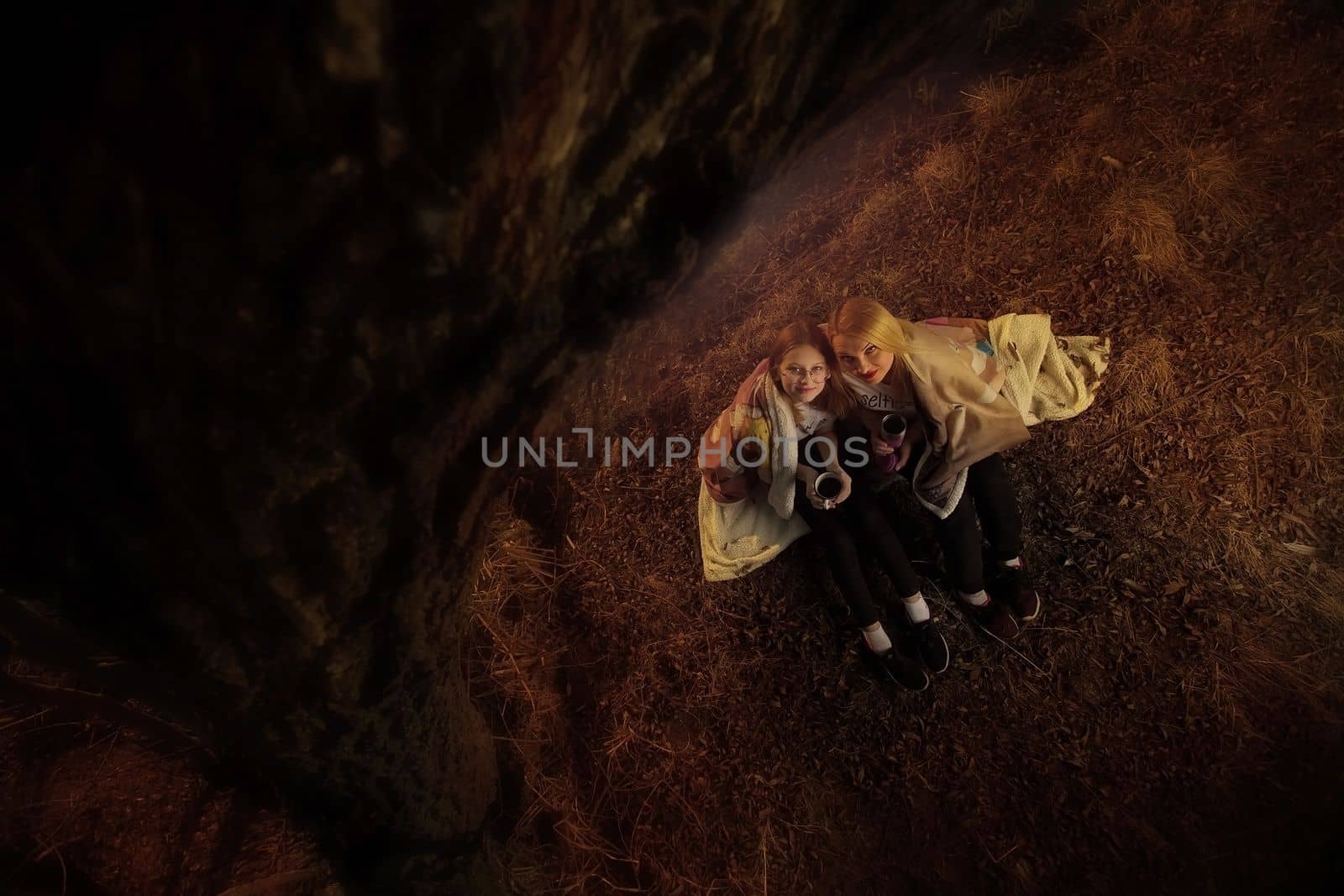 The family, mother and daughter, for the weekend went out into the countryside for a picnic, sit by the fire in the wild with a tent, fry potatoes, drink hot tea. High quality photo