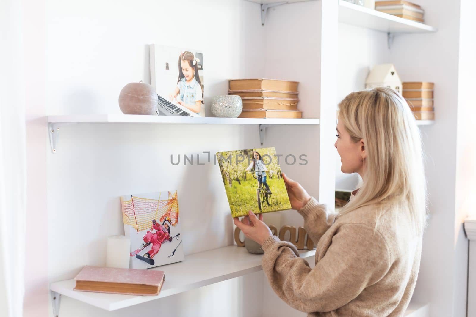 Young woman hanging a photo canvas print painting on the wall.