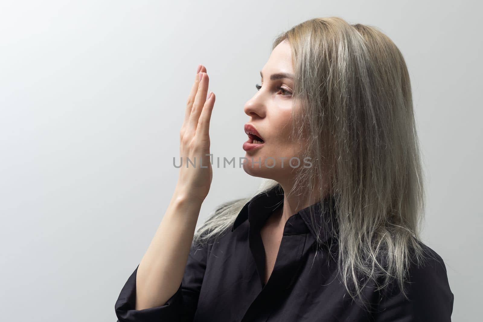 Health Care: Woman checking her breath with her hand.