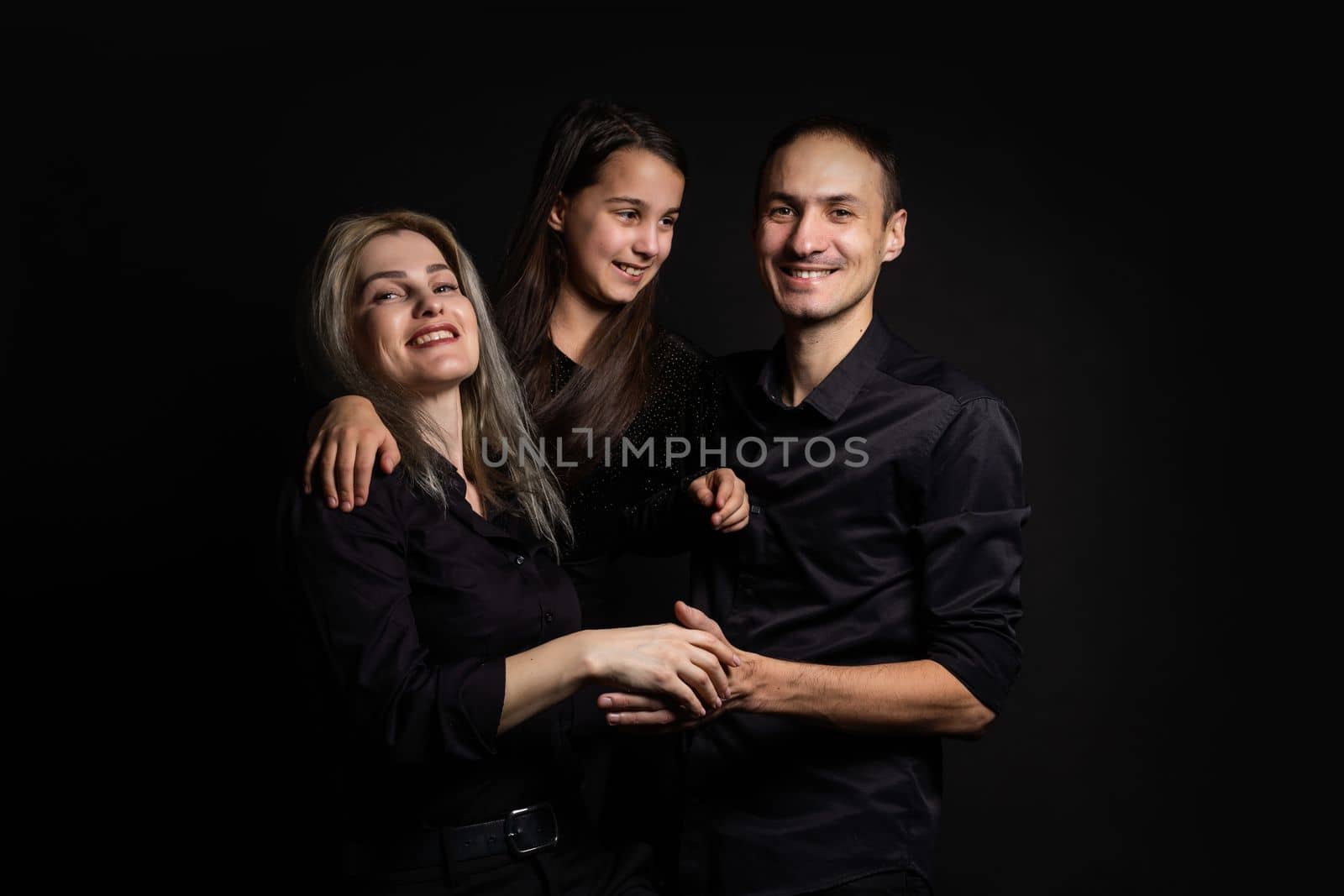 happy family mother, father, daughter on a black background.
