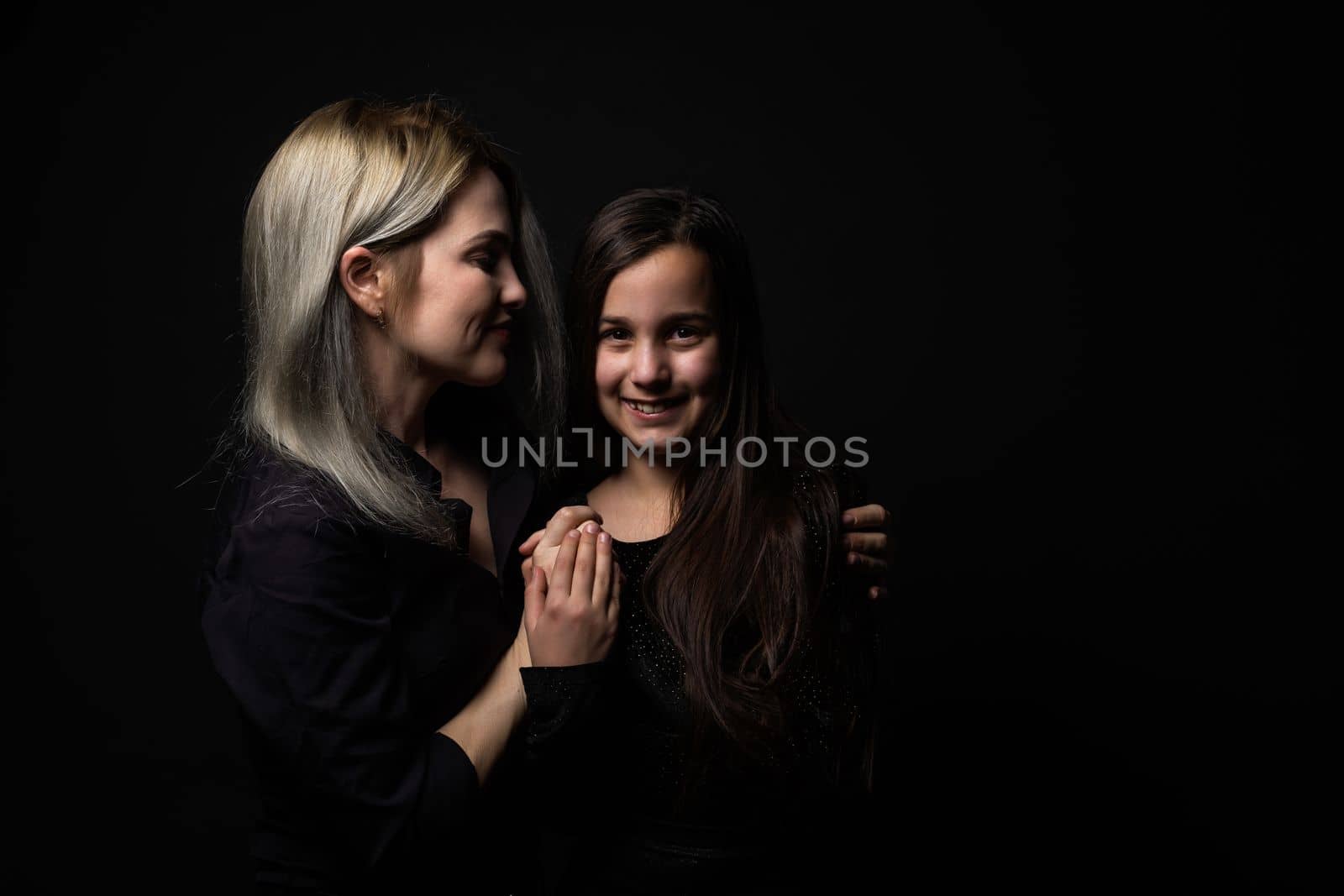 a little girl with her mother is praying while hugging.