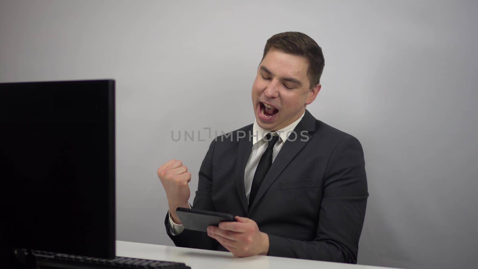 A young programmer plays a game on the phone. Businessman plays at work in the office plays smartphone. 4k