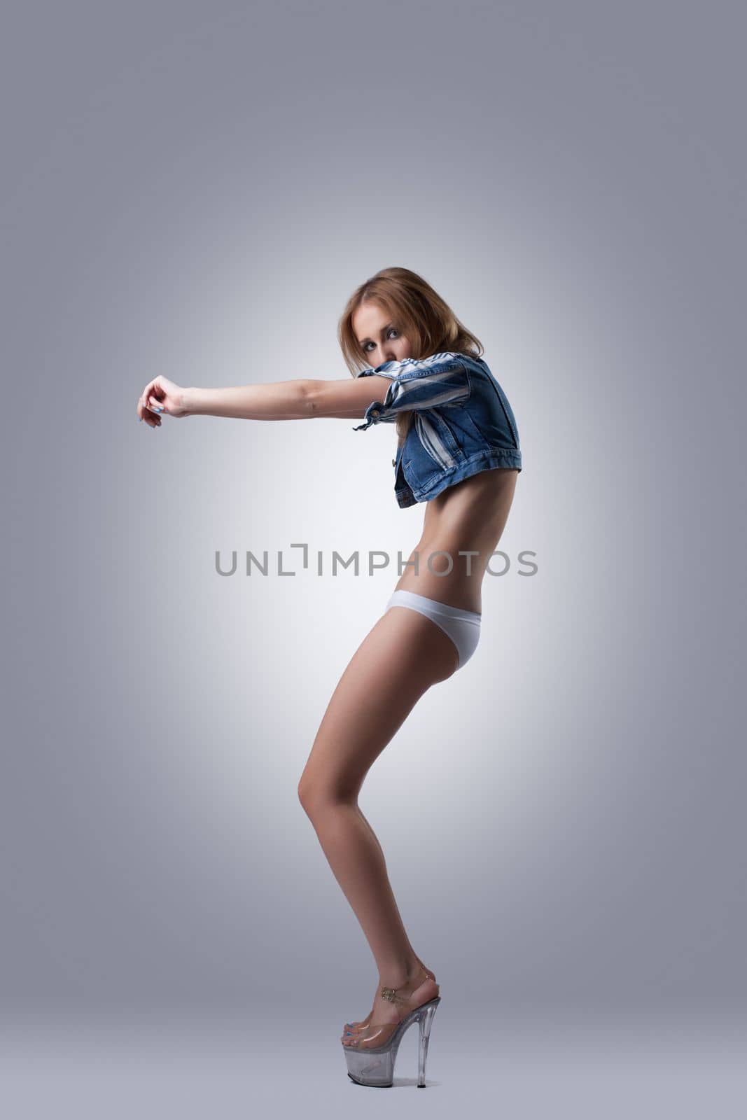 Sexy young woman in white bikini and denim jacket dance
