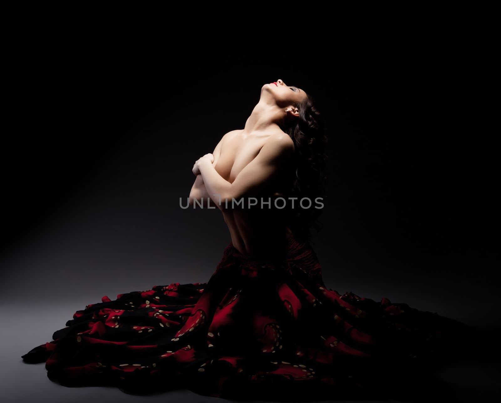 Beautiful topless woman posing in flamenko skirt, on black background