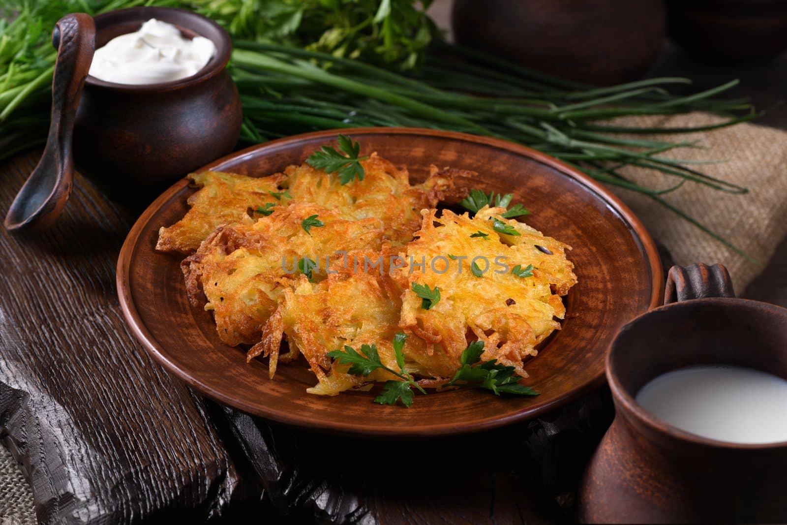 Potato fritters (a pancake, especially one made with grated potato) served with sour cream, herbs and a jug of milk. Country style.