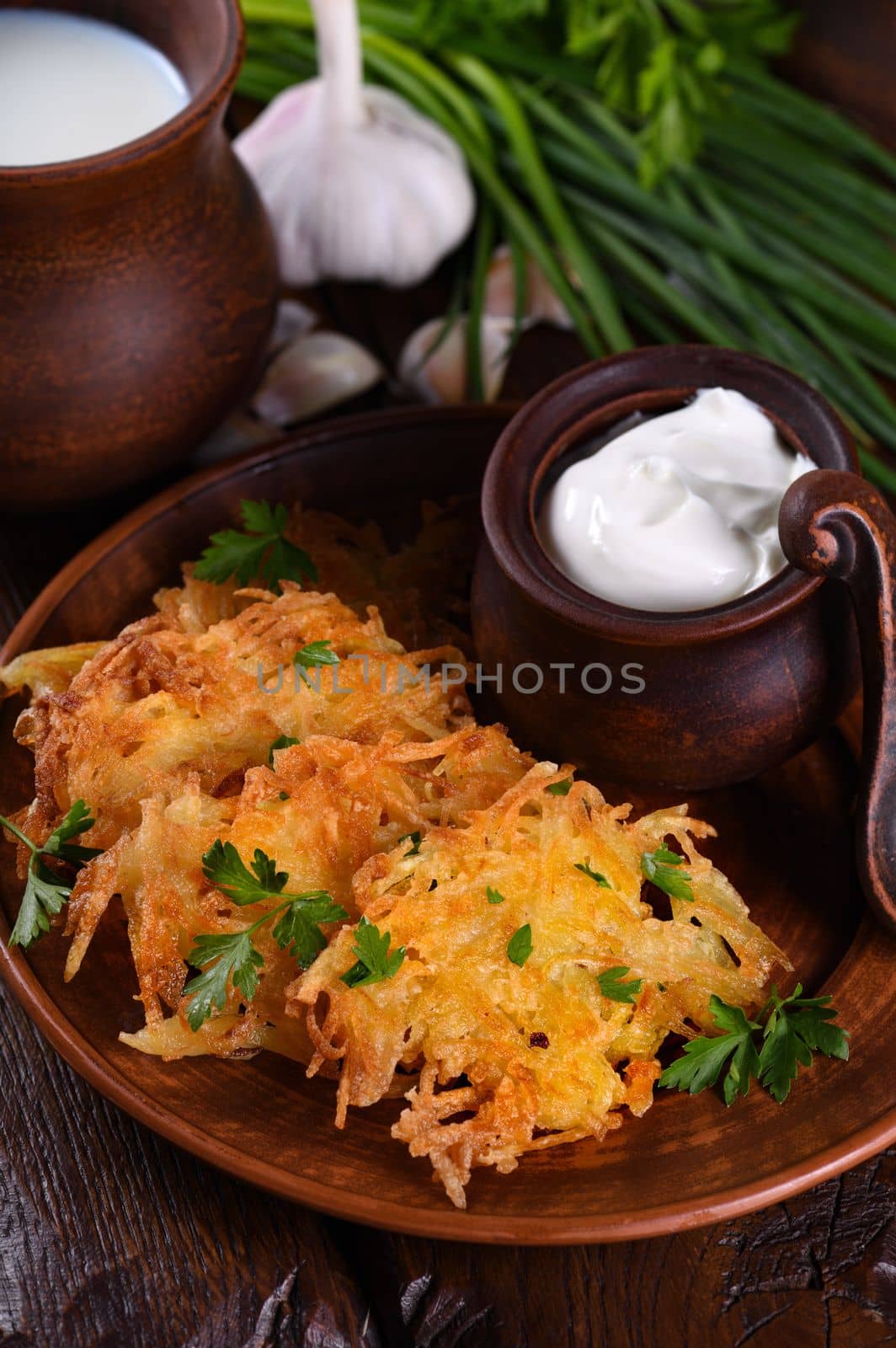 Potato fritters (a pancake, especially one made with grated potato) served with sour cream, herbs and a jug of milk. Country style.