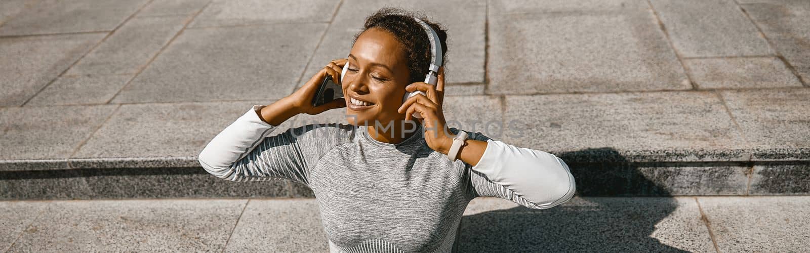Sporty woman in headphones listening to music after training outdoors. Active lifestyle