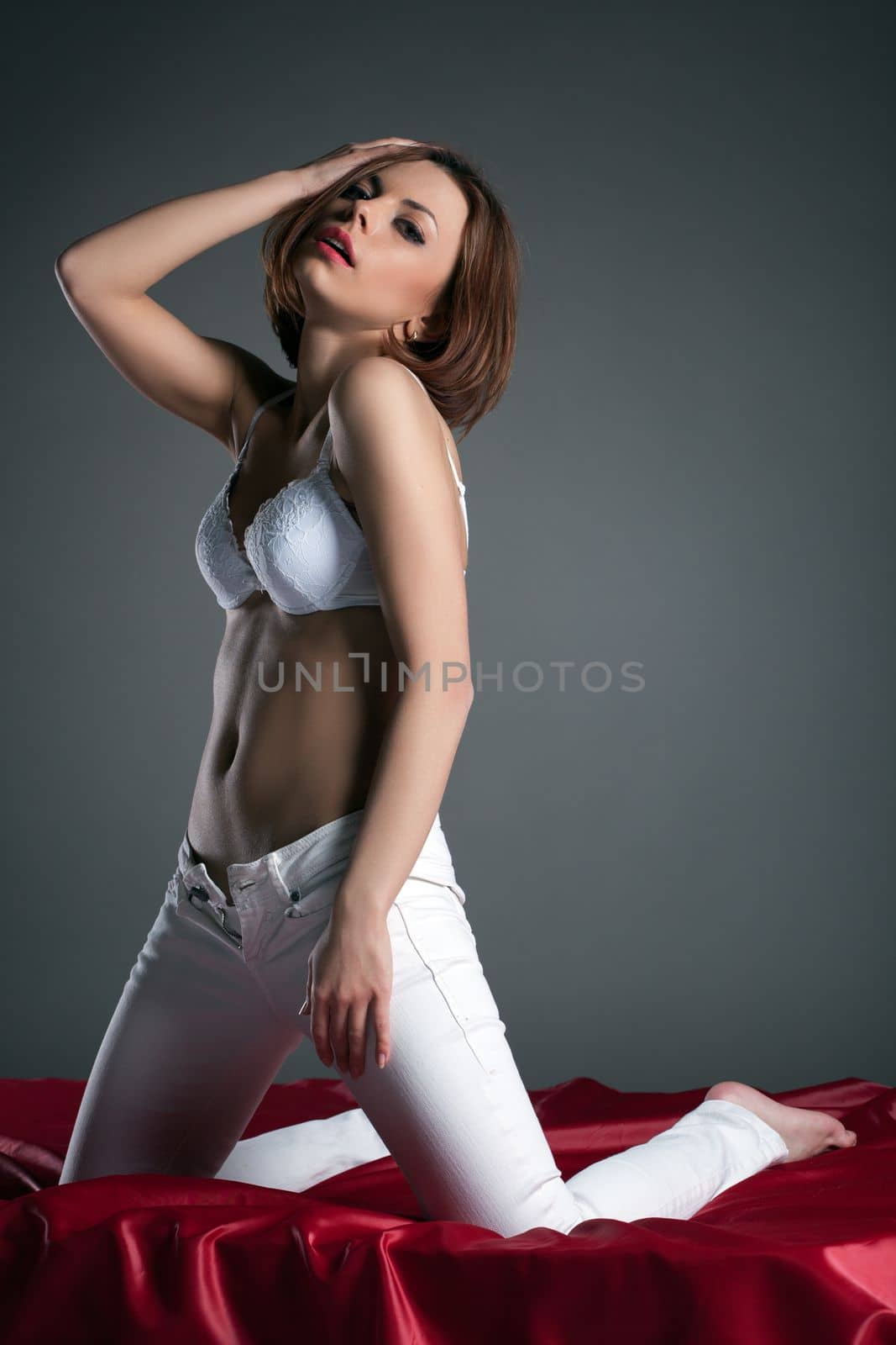 Young sensual woman posing in white clothes, on gray background