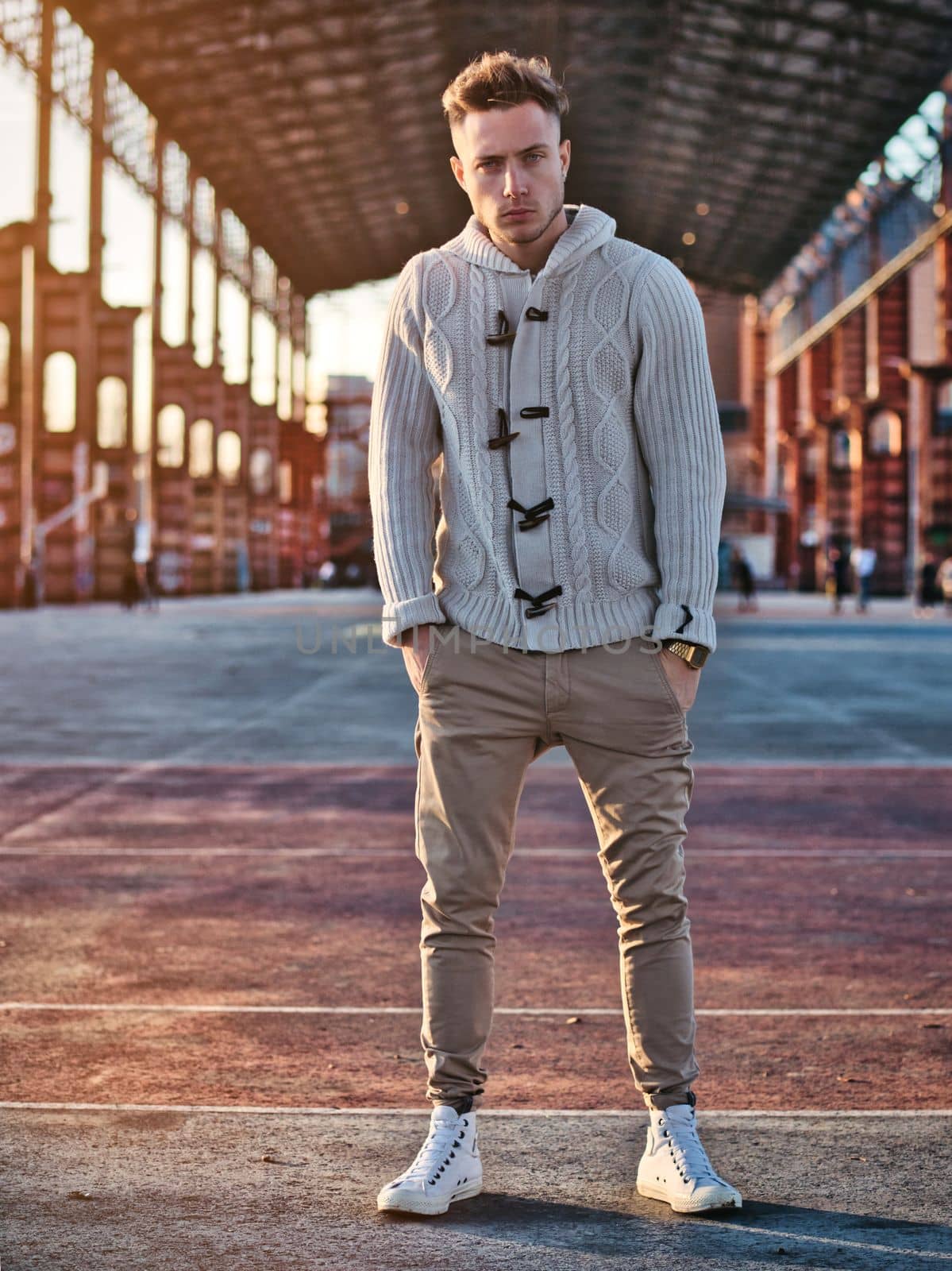 Handsome young man standing in modern urban setting, looking at camera, with winter cardigan