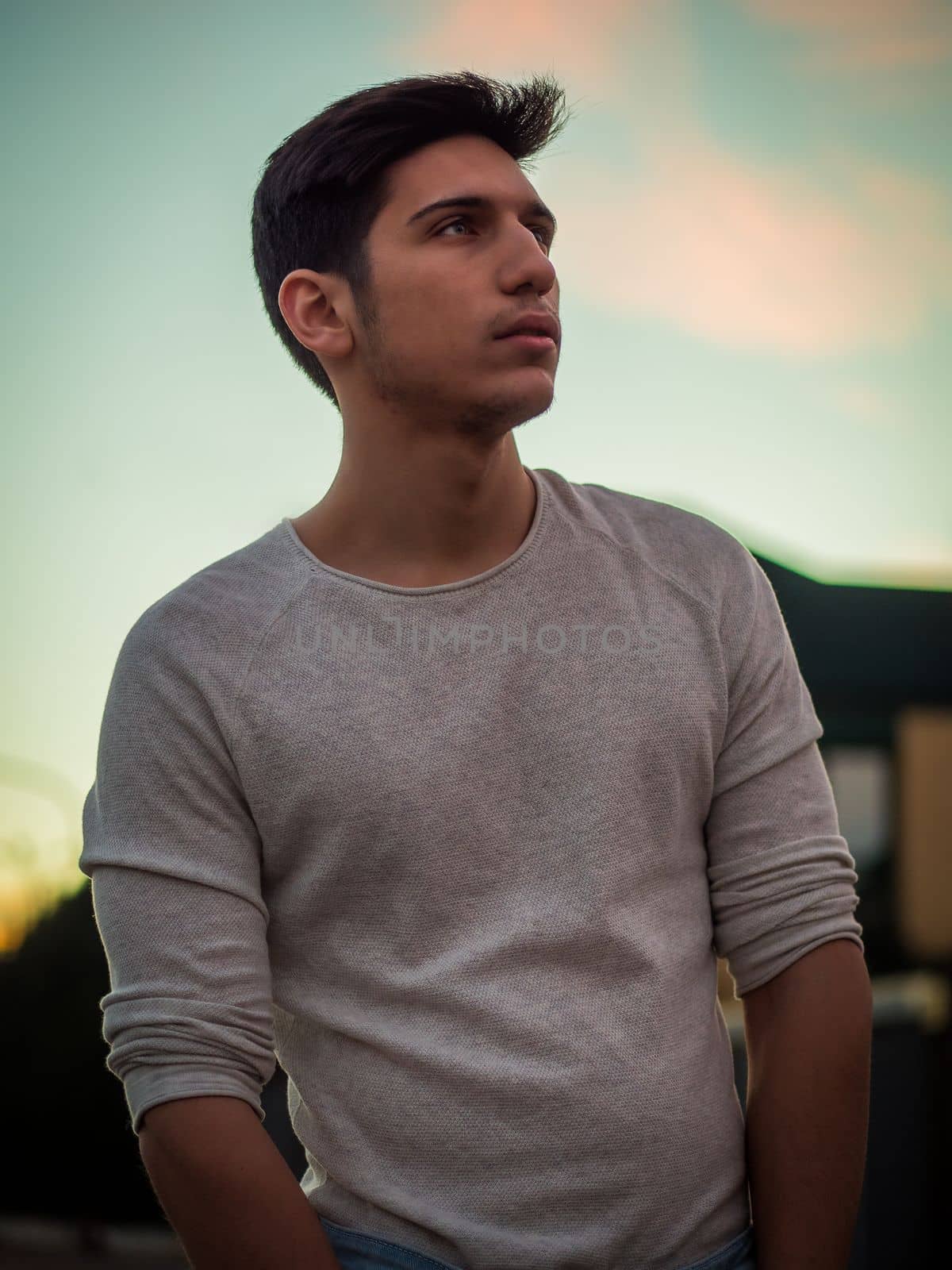 Handsome young man in white sweater outdoor in street by artofphoto