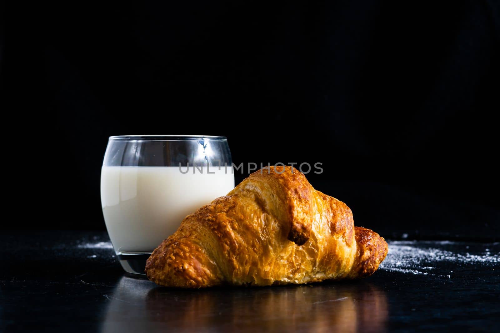 Fresh white bread and milk in white glass on black stone table background. Top view and Studio shot by Zelenin