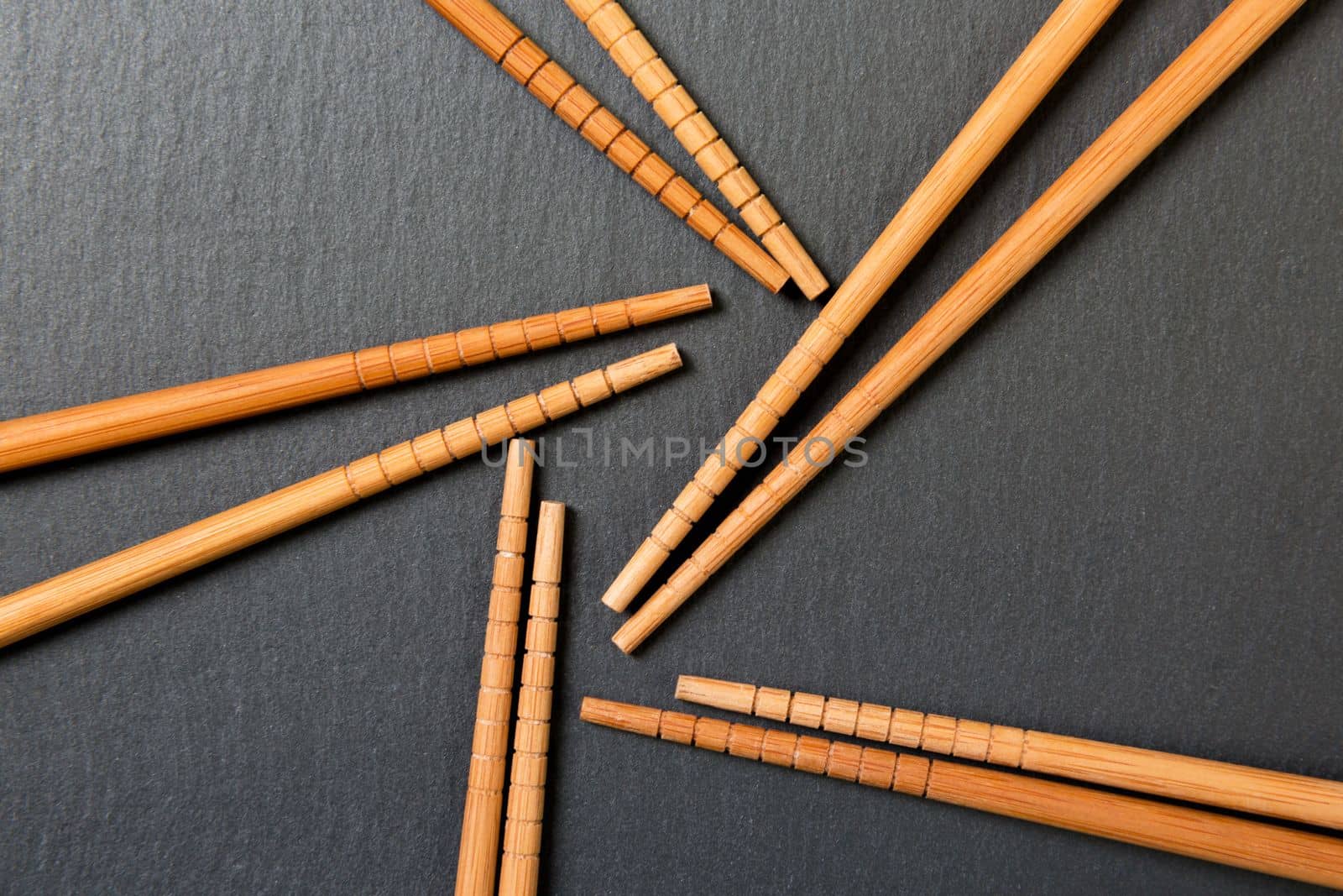 Many bamboo chopsticks on black slate background, textured, top view with opy space.