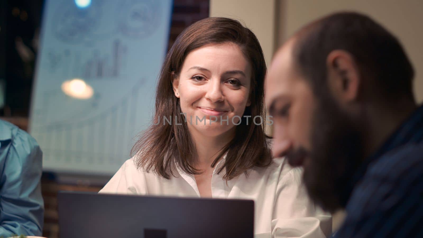 Woman talking with employee in business meeting, smiling portrait, slow motion. Colleagues discussion, brainstorming, communication in coworking space, office manager looking at camera. Handheld shot.