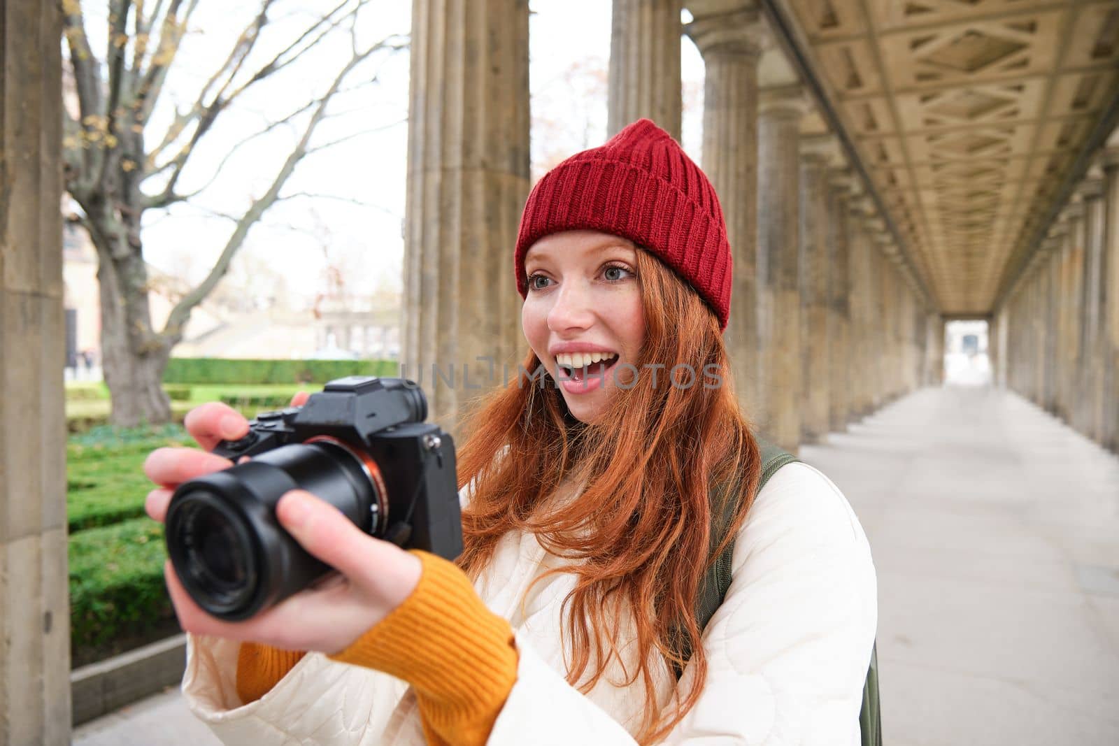 Smiling tourist photographer, takes picture during her trip, holds professional camera and makes photos. Copy space