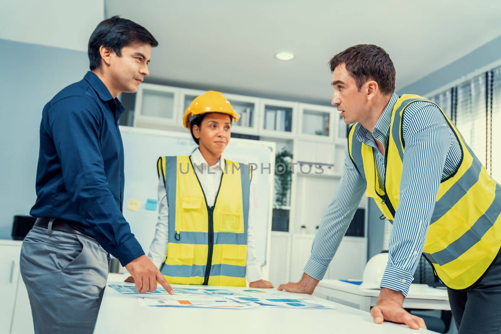 A group of competent engineers and employer discuss plans in the office. Architectural investor, businessman, and engineer discussing blueprints.