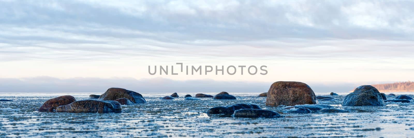 Panoramic view of the snow-covered shore of the Baltic sea at sunset. Ice fragments at sea close-up. by PhotoTime