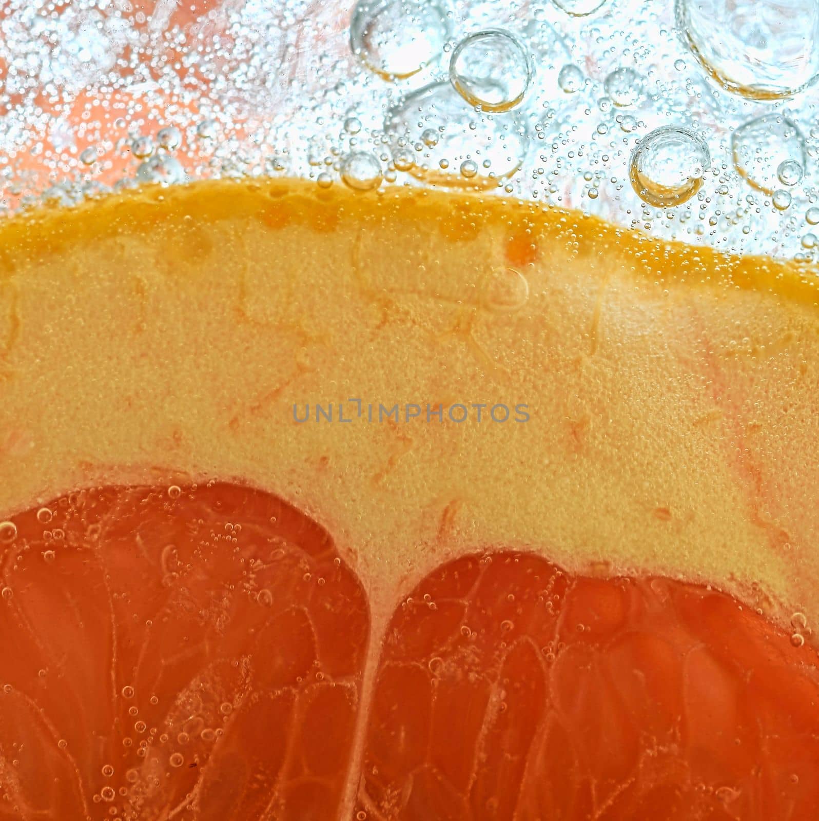 Close-up of fresh grapefruit slice on white background. Slice of red grapefruit in sparkling water on white background, close-up. Horizontal image by roman_nerud