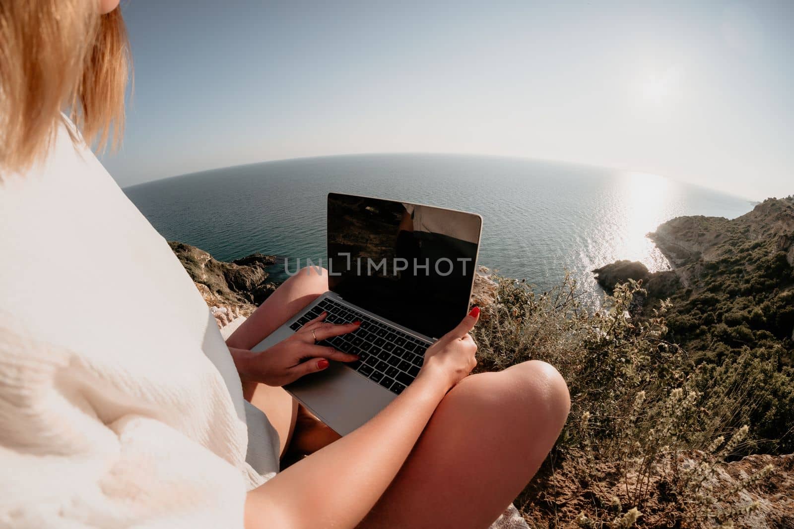 Woman sea laptop. Business woman in yellow hat working on laptop by sea. Close up on hands of pretty lady typing on computer outdoors summer day. Freelance, digital nomad, travel and holidays concept.