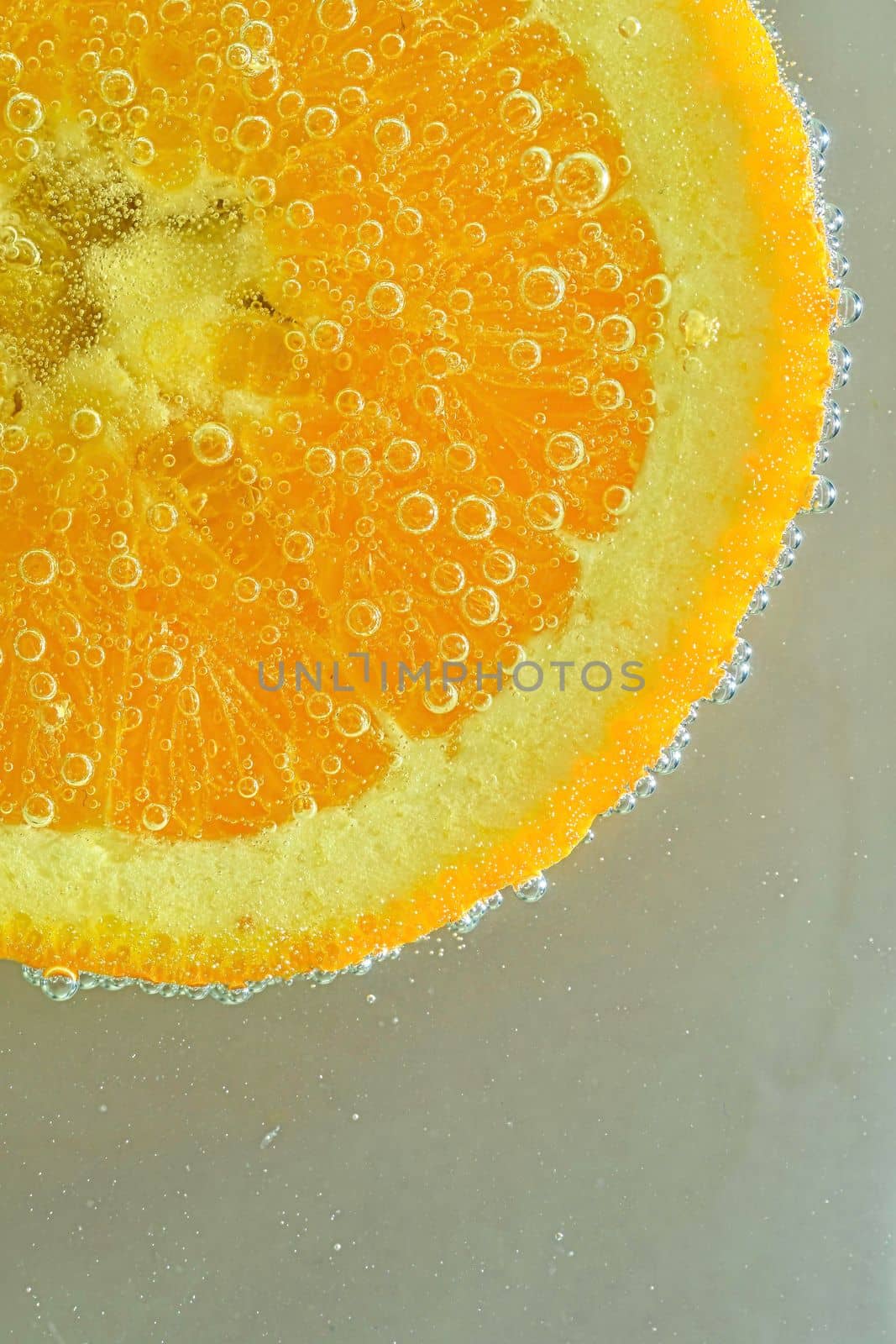 Close-up of fresh orange slice on white background. Slice of orange in sparkling water on white background, close-up. Horizontal image.ice in liquid with bubbles. Slice of orange fruit in water. Close-up of fresh orange fruit slice covered by bubbles. Vertical image.