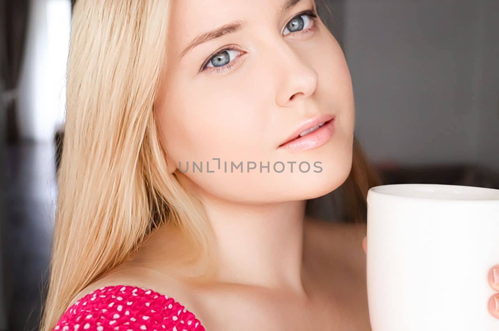 Beautiful blonde woman having a cup of tea in the morning at home.