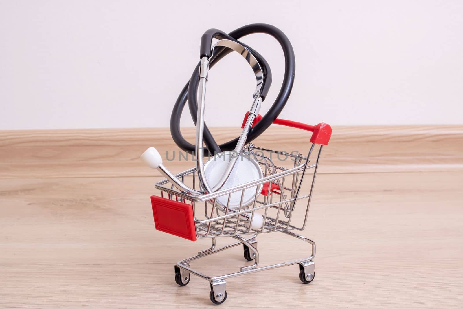 Stethoscope in shopping cart on wooden background close up