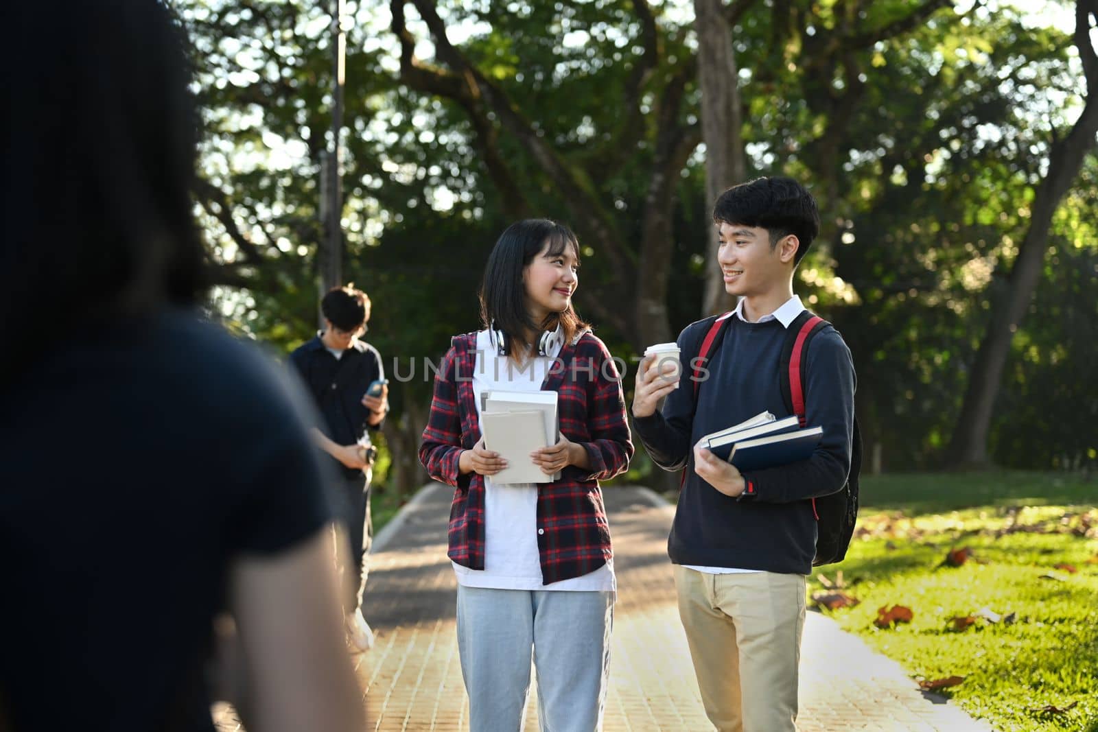 Two asian college students having break after classes and twirling in campus. Youth lifestyle and friendship concept by prathanchorruangsak