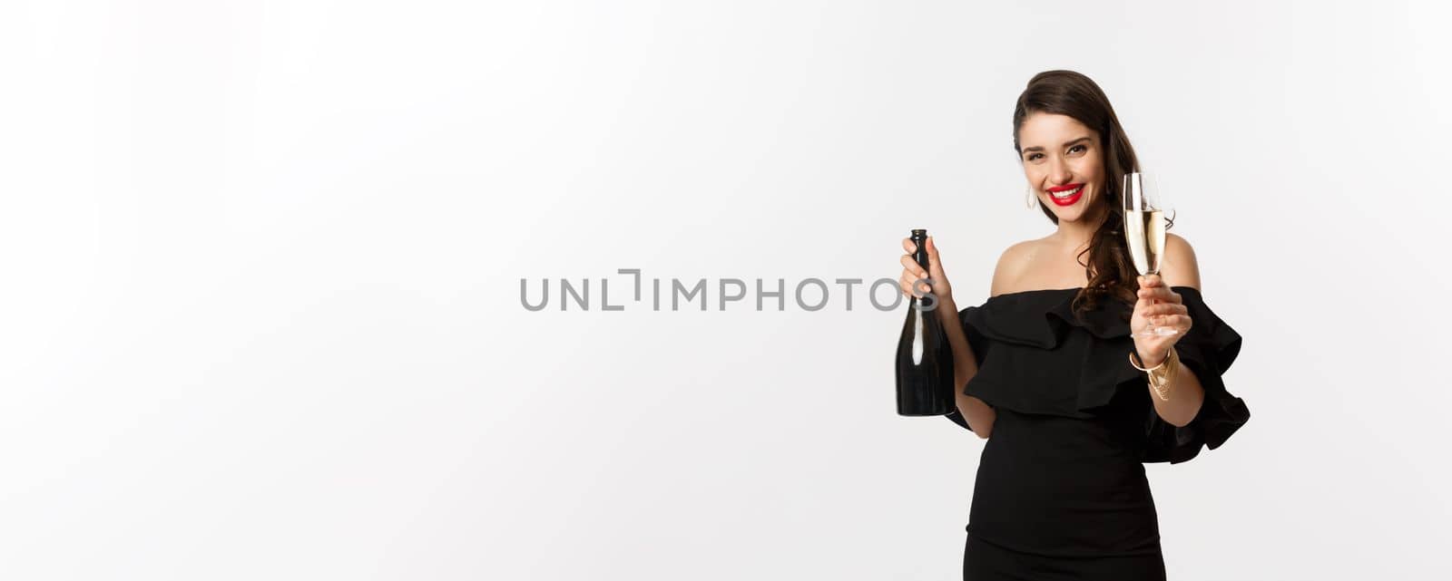 Celebration and party concept. Happy woman enjoying New Year, raising glass of champagne and saying toast, standing in black dress over white background.