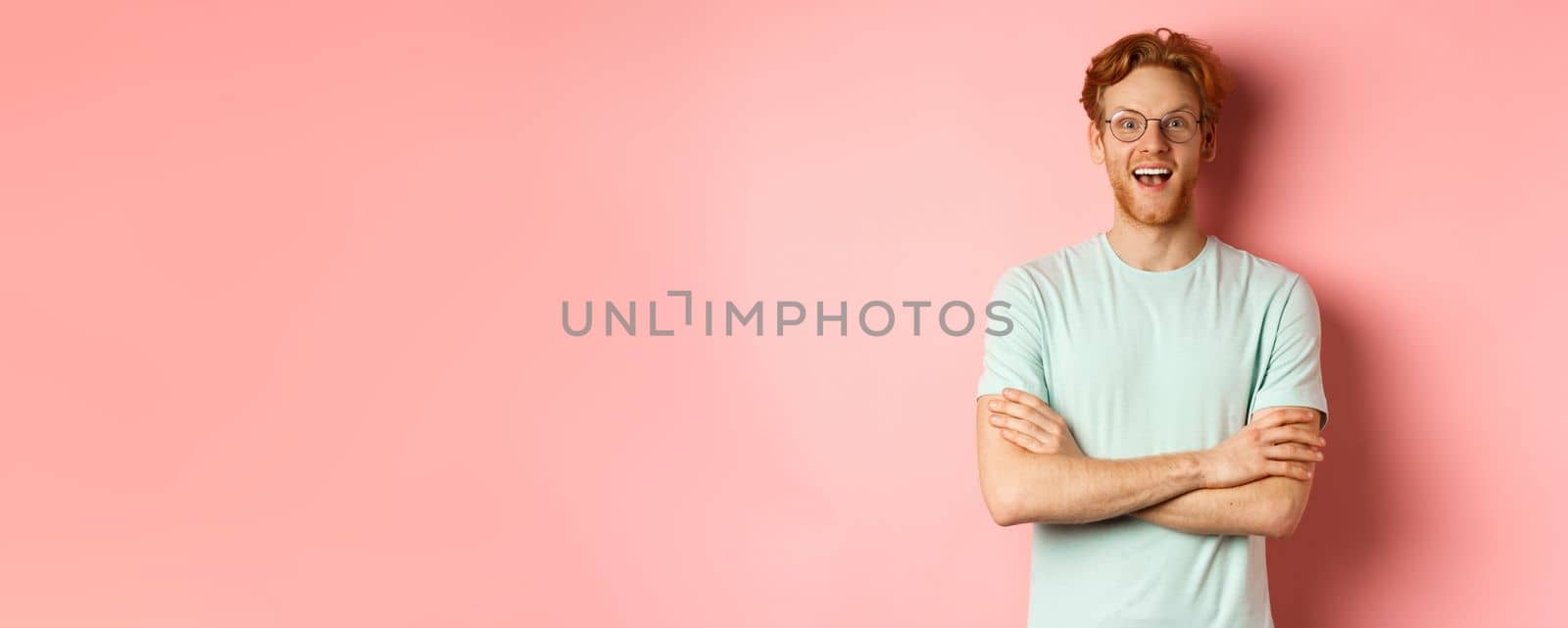 Portrait of cheerful european man in glasses looking amazed at camera, see interesting promotion, standing amused over pink background by Benzoix