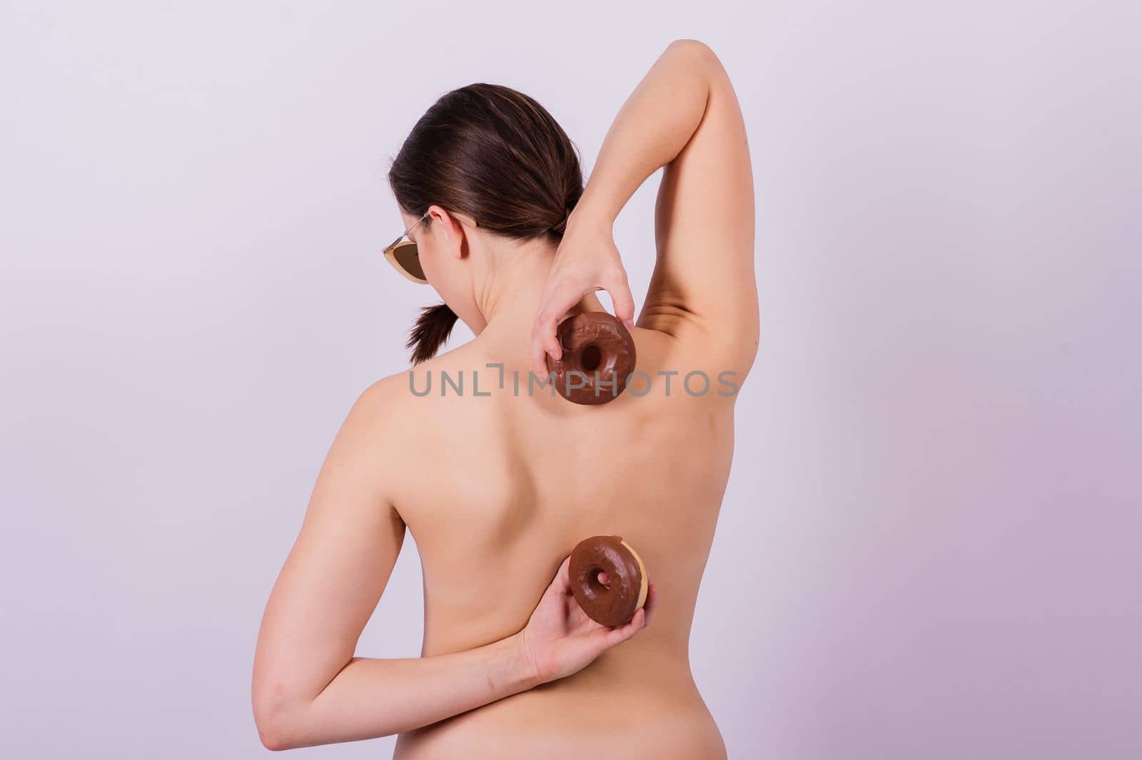 Close up shot of nude woman's body with a chocolate covered donuts by Zelenin