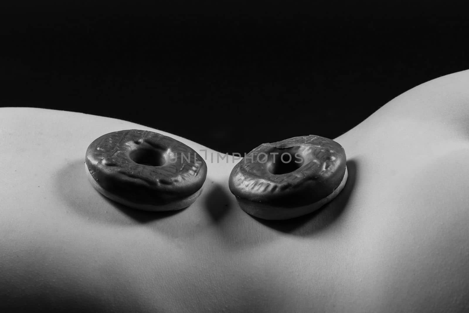 Close up shot of nude woman's body with a chocolate covered donuts by Zelenin