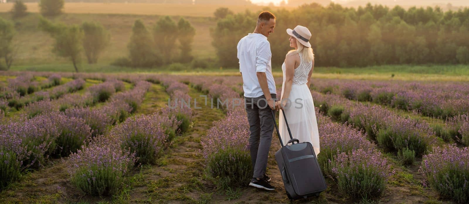 man and woman with suitcase in lavender field.