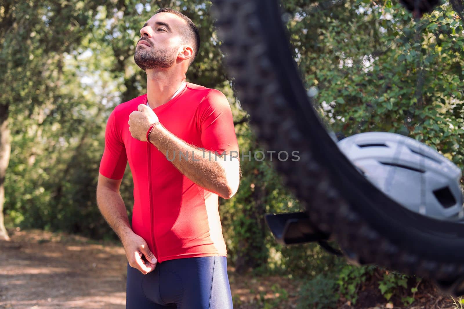 young man dressing up with cycling clothes next to his mountain bike to go training, concept of freedom and sport in nature