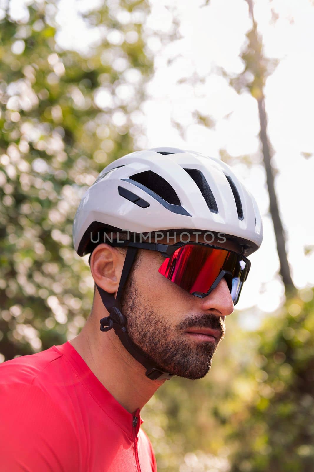 portrait of a young man wearing a helmet and cycling goggles in the middle of the forest, concept of freedom and sport in nature, copy space for text