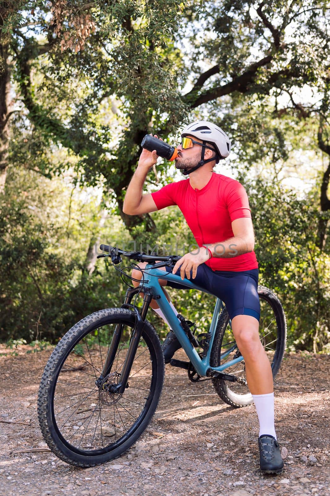 young cyclist drinking water while resting during his mountain bike training ride, concept of freedom and sport in nature