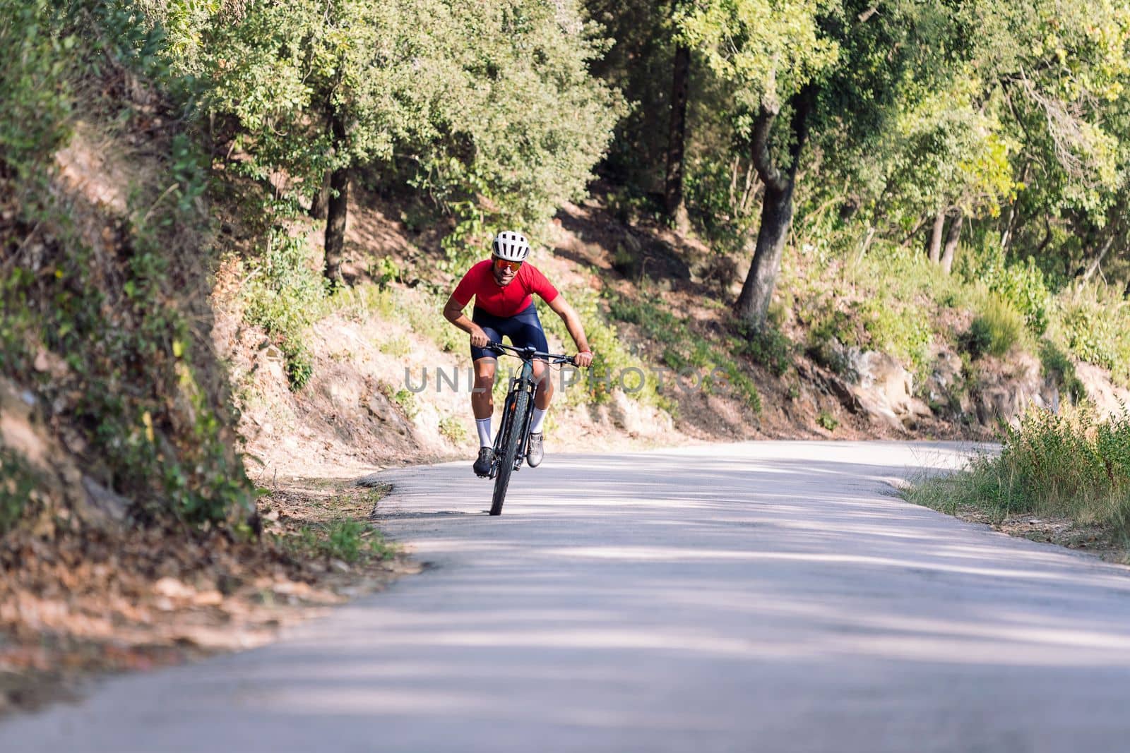 young cyclist training hard with his mountain bike on a forest road, concept of freedom and sport in nature, copy space for text