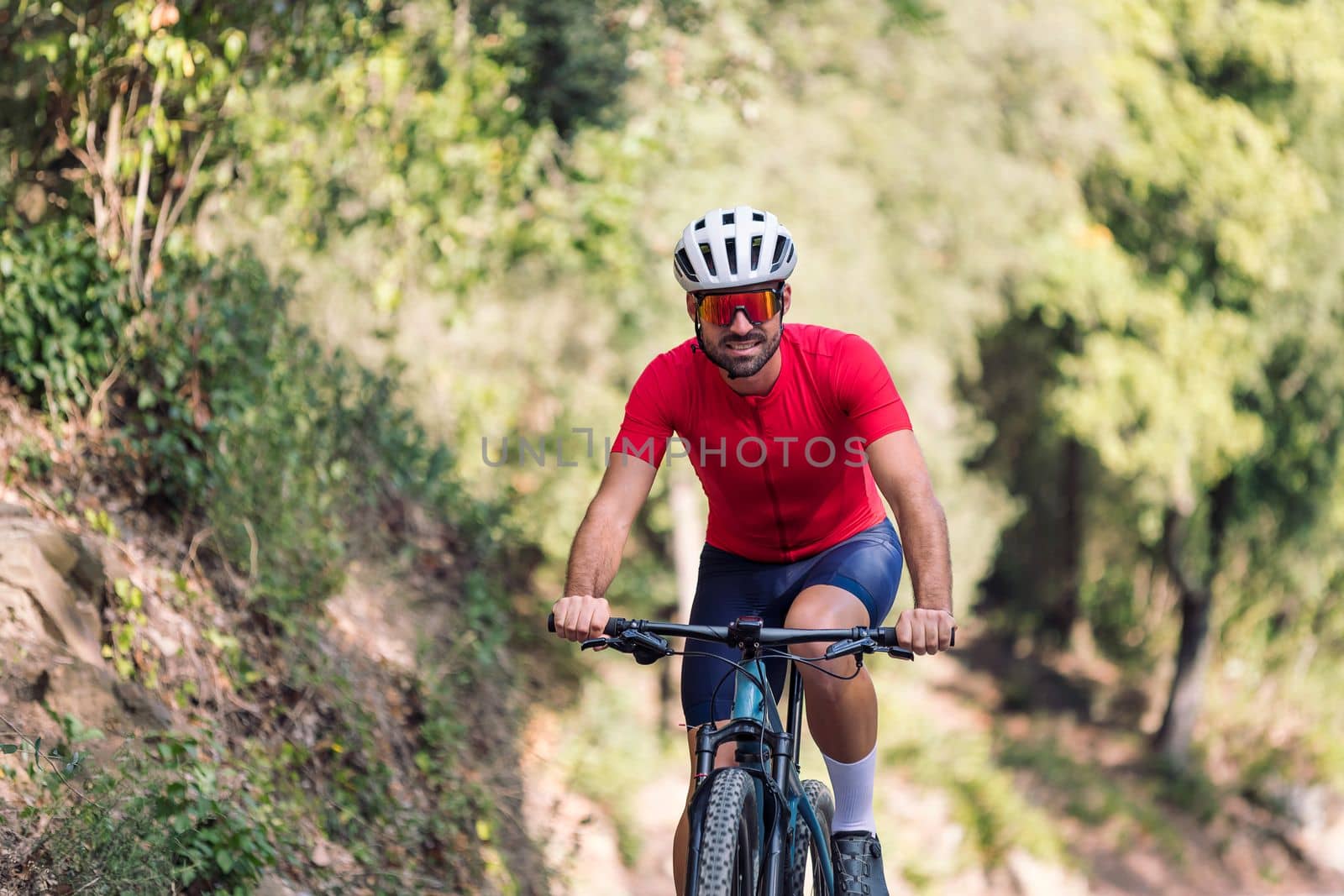 young cyclist riding relaxed with his mountain bike by a forest, concept of freedom and sport in nature, copy space for text