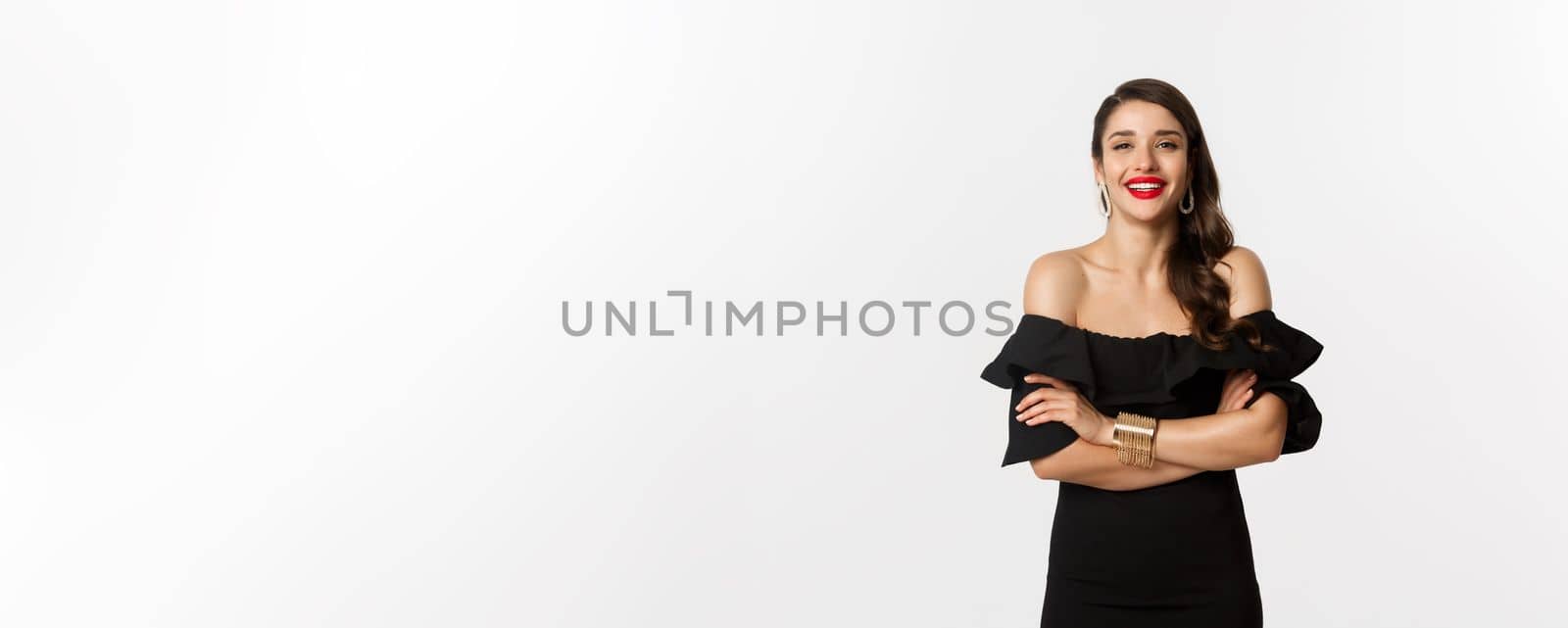 Beauty and fashion concept. Attractive female model in party dress and red lipstick, smiling pleased, looking happy, standing over white background.