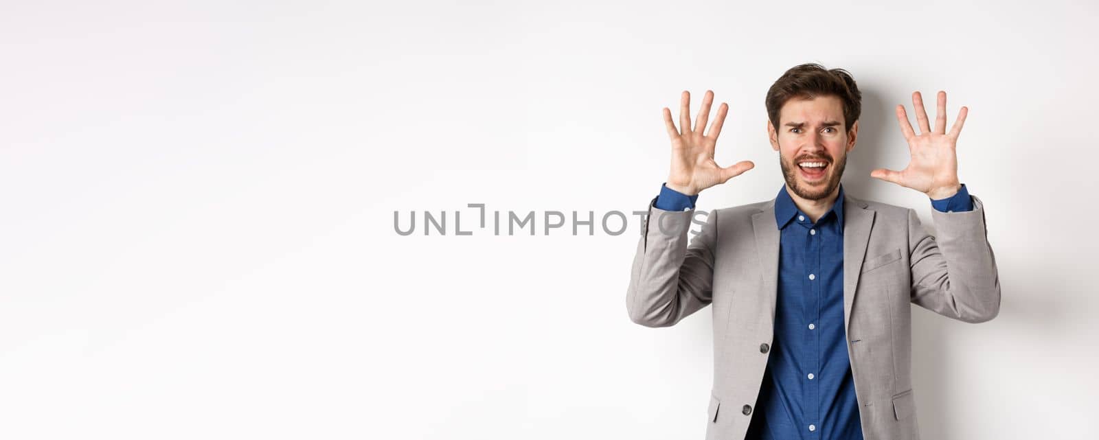 Frustrated man giving up, raising hands up in surrender and screaming, having argument, wearing suit and looking distressed, white background.