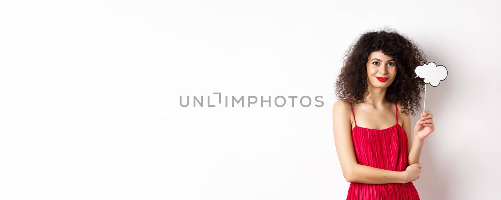 Elegant woman with curly hair, wearing red evening dress, holding cloud and smiling, standing on white background by Benzoix