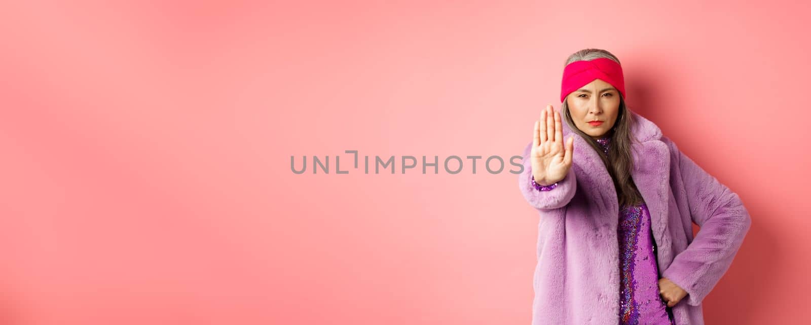 Fashion and shopping concept. Serious asian senior woman showing stop sign to warn and prohibit something, looking determined at camera, wearing stylish purple clothes by Benzoix