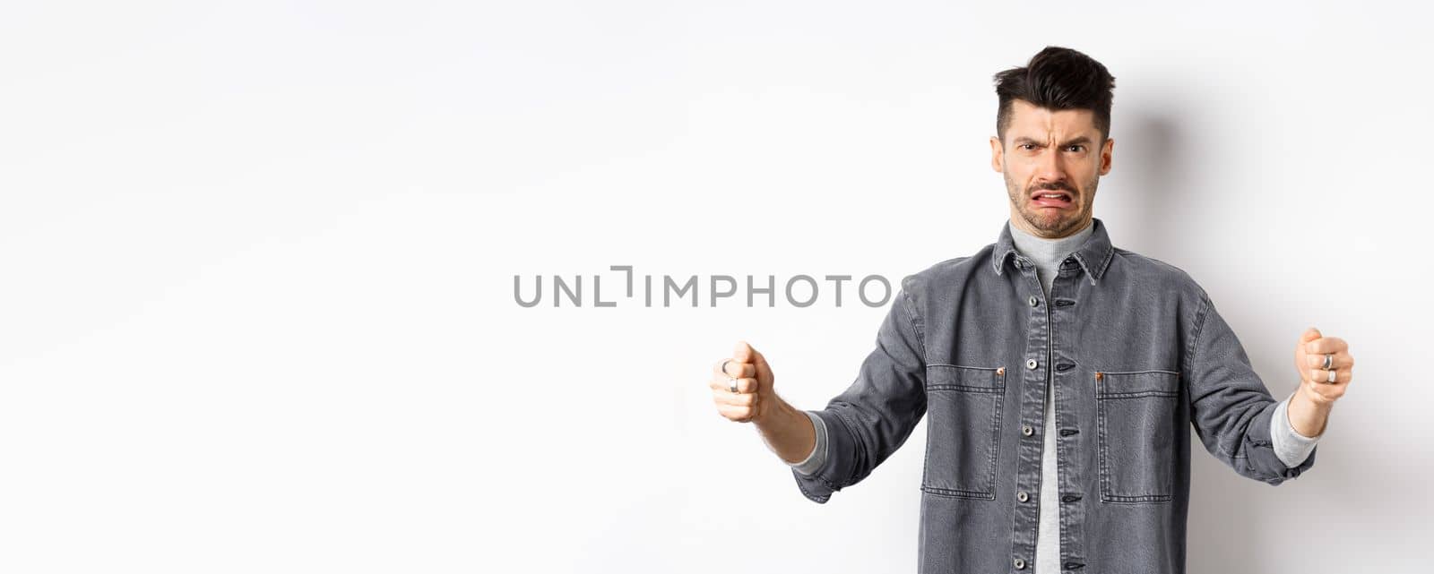 Disgusted guy showing big size object and grimacing from dislike and aversion, talking about disgusting large thing, standing on white background by Benzoix
