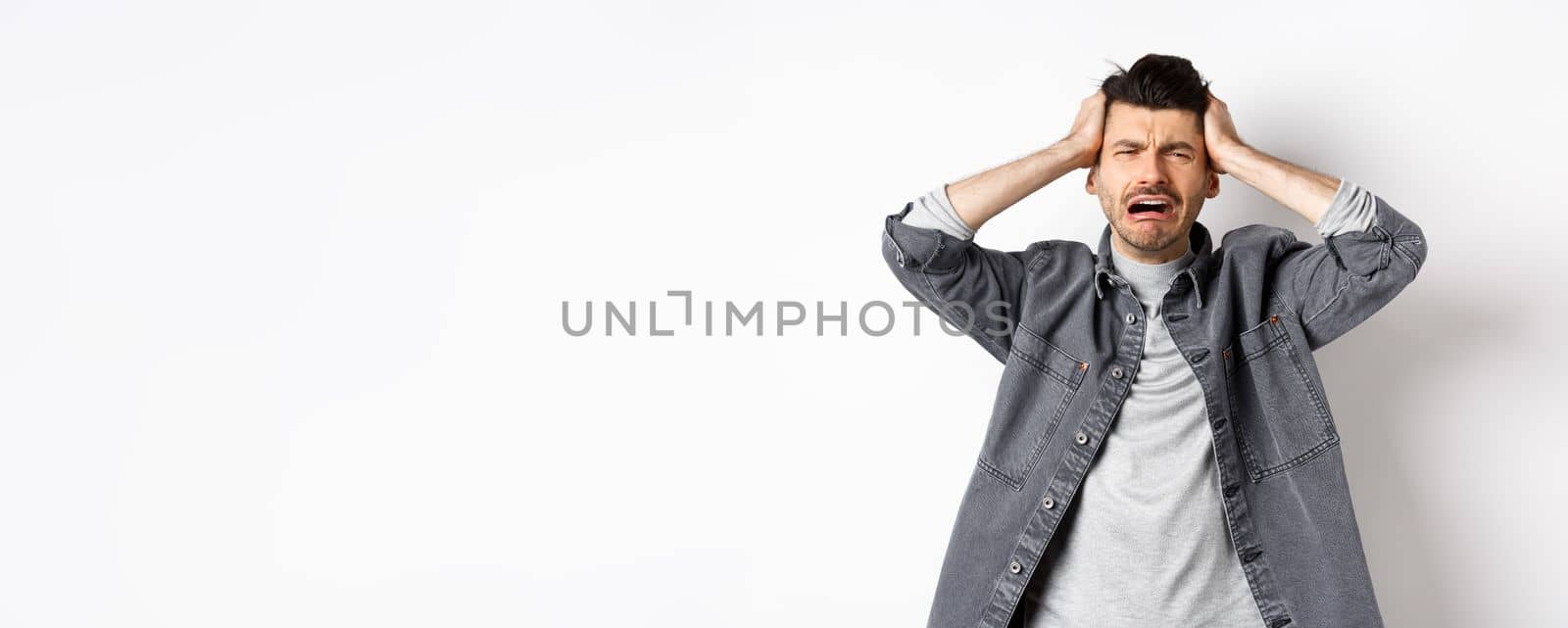 Frustrated guy crying and panicking, holding hands on head and screaming distressed, having trouble, standing upset on white background by Benzoix