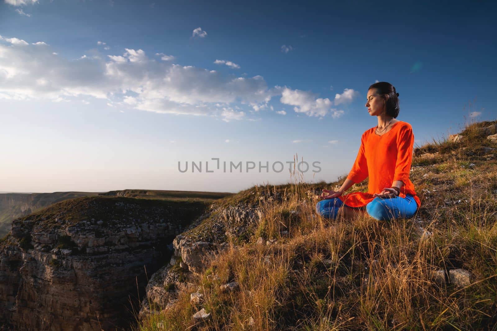 Woman practices yoga and meditates on the mountain by yanik88