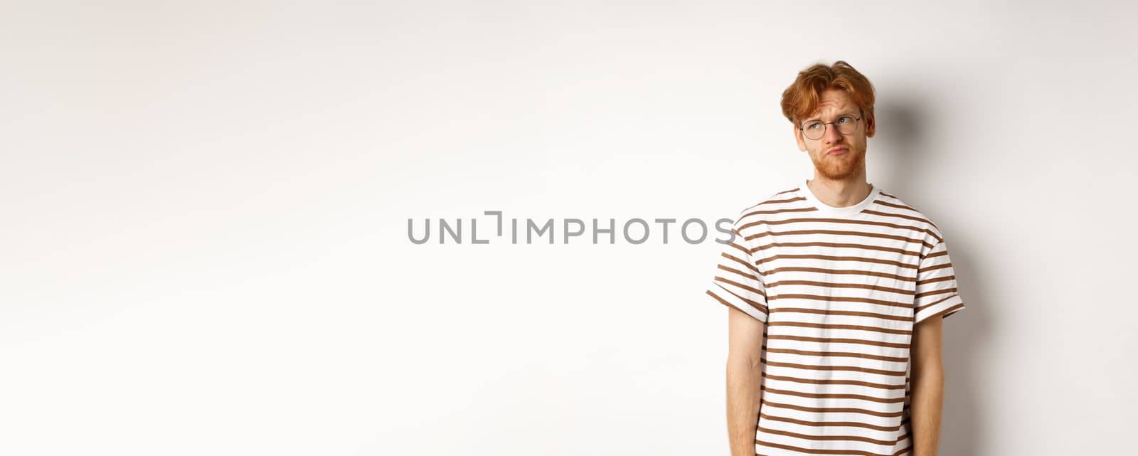 Sad and gloomy redhead man looking upper left corner, sulking and feeling like loser, standing over white background by Benzoix