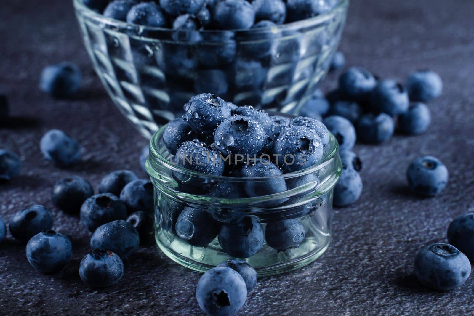 Blueberries organic natural berry with water drops on dark background close-up. Blueberry in glass bowl plate. by Rabizo