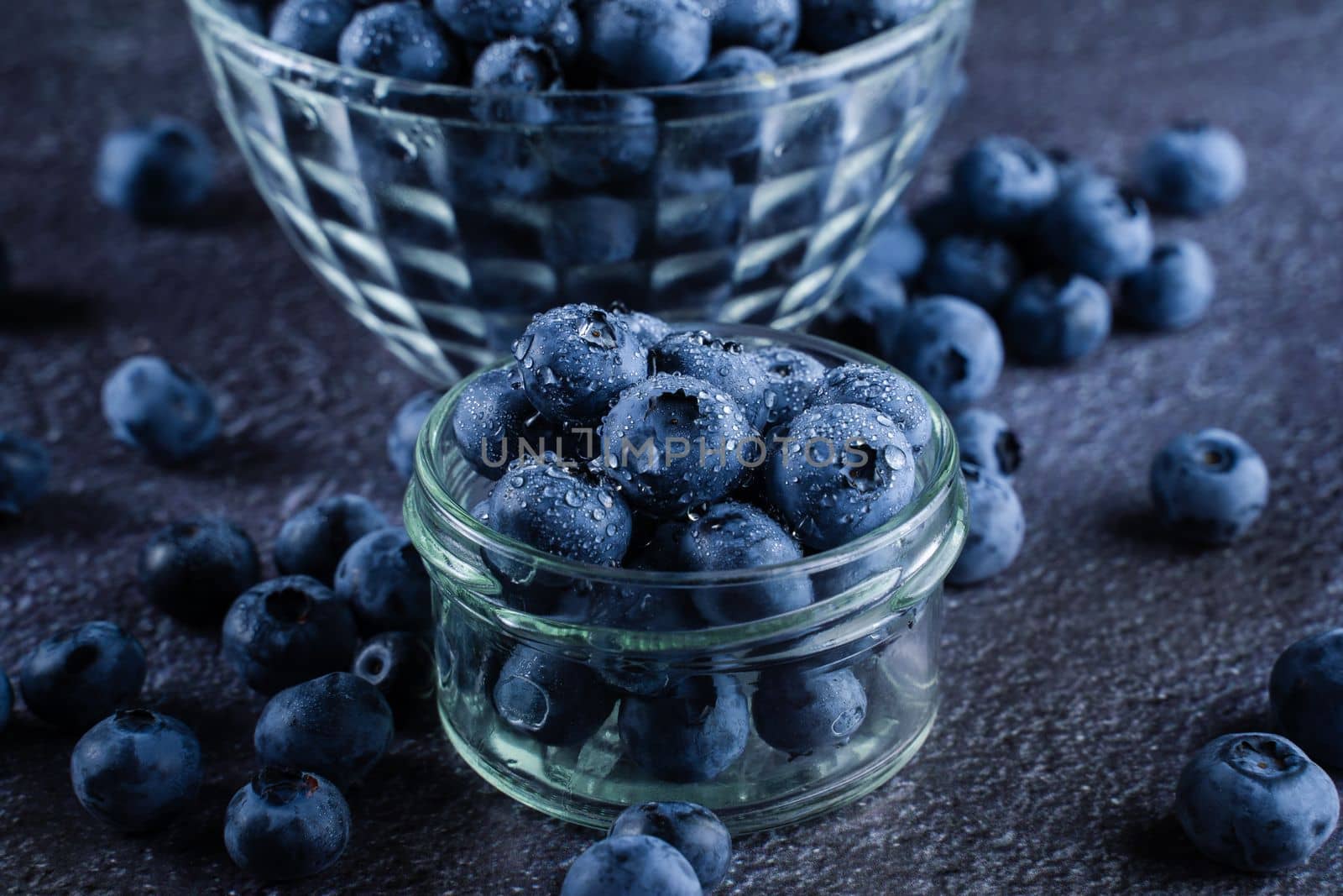 Blueberries organic natural berry with water drops on dark background close-up. Blueberry in glass bowl plate