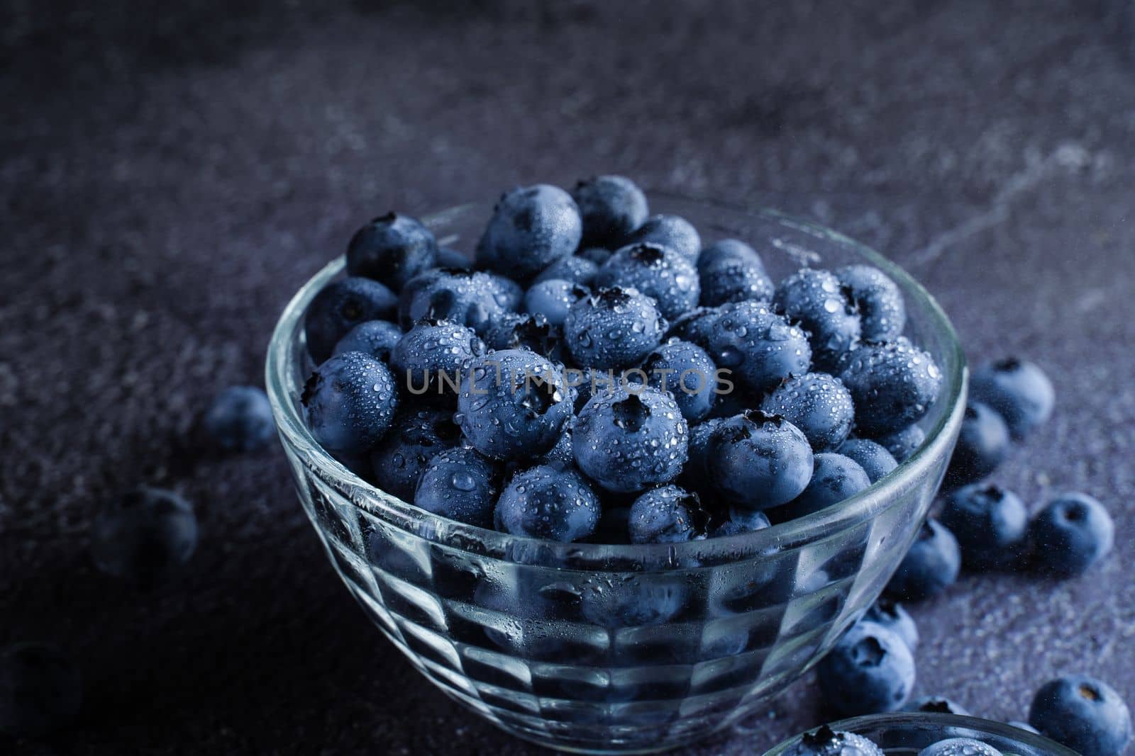 Blueberries organic natural berry with water drops on dark background. Blueberry in glass bowl plate