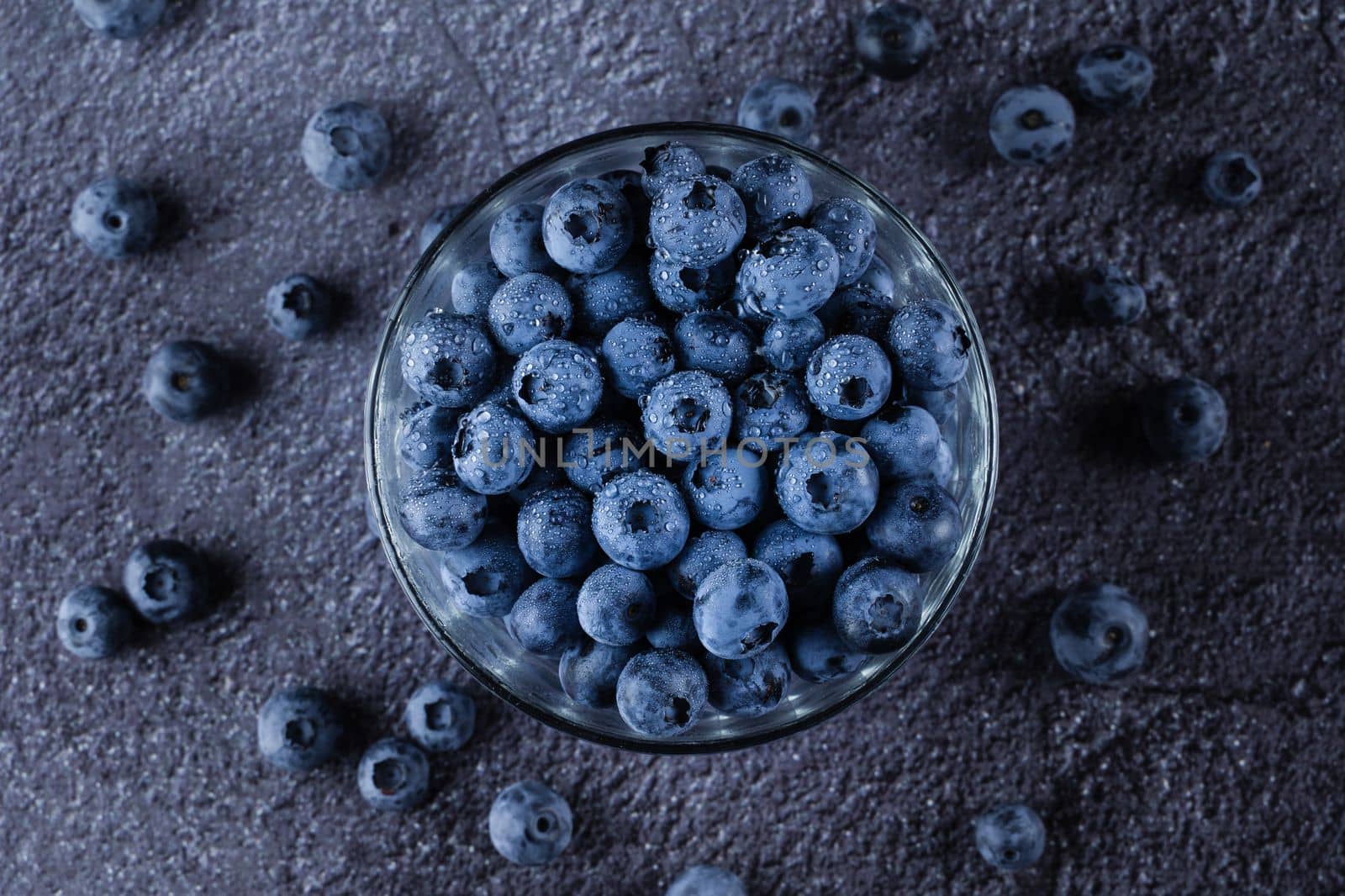 Blueberry in glass plate top view. Blueberries organic natural berry with water drops on dark background by Rabizo