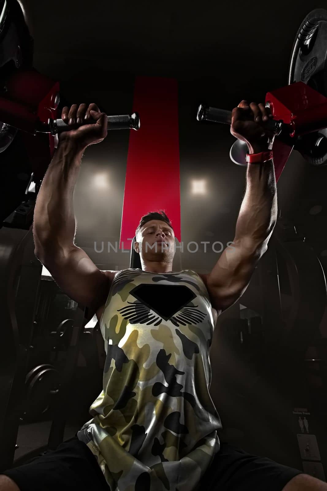 bodybuilder goes in for sports in the gym on a simulator in a T-shirt, creative photo