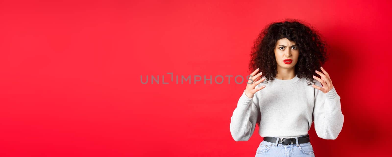 Angry caucasian woman frowning and raising hands mad, wants to strangle or kill someone annoying, standing on red background by Benzoix